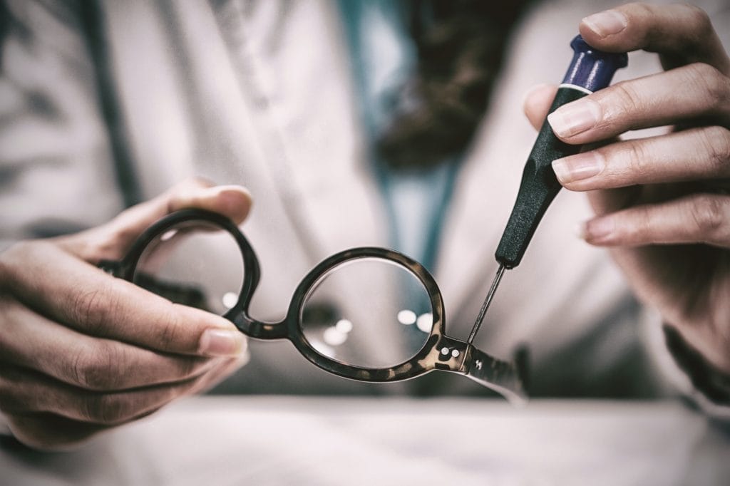 Optician repairing spectacles with tool