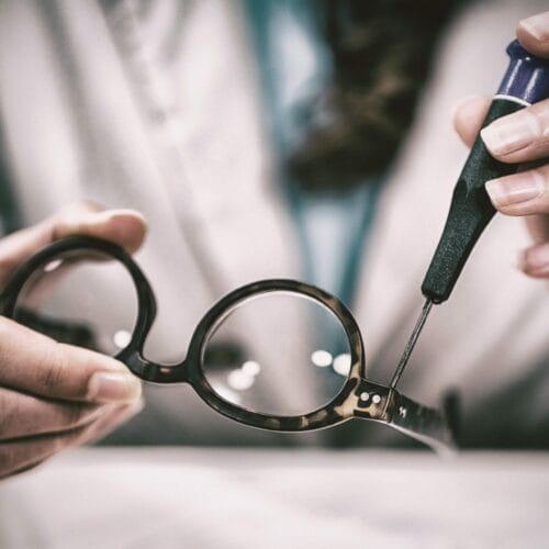 Optician repairing spectacles with tool