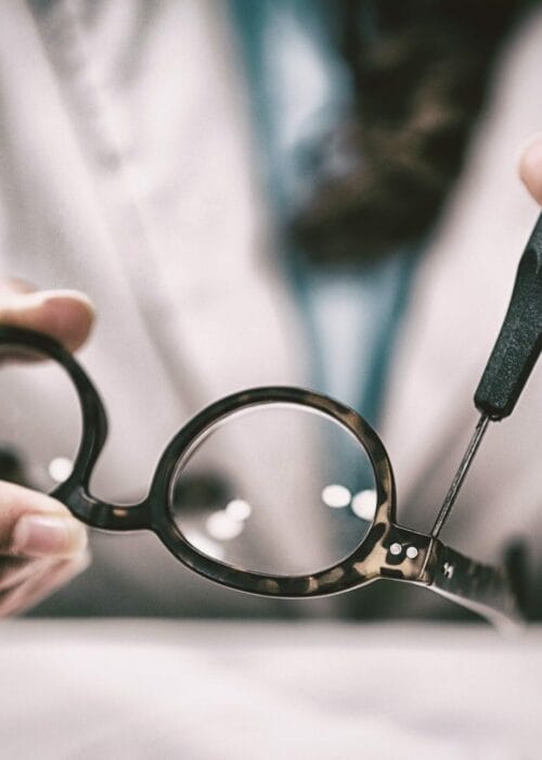 Optician repairing spectacles with tool